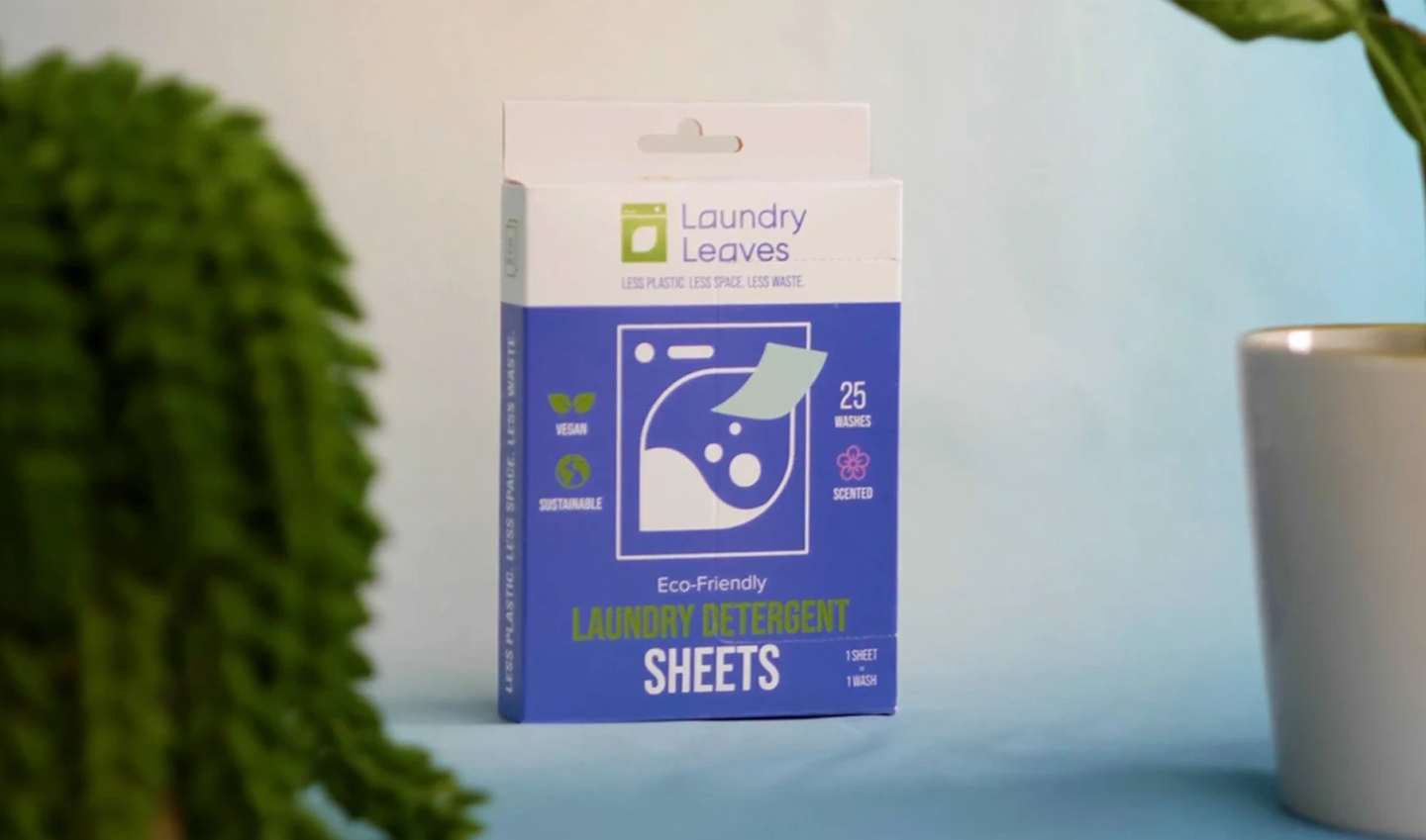 A box of Laundry Leaves sheets behind two plants